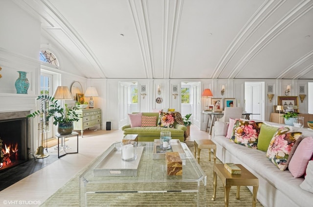 living area with a high end fireplace, a decorative wall, wood finished floors, plenty of natural light, and lofted ceiling