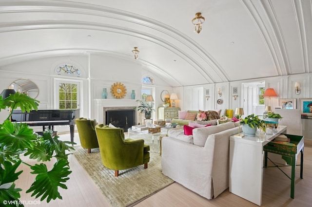 living room featuring a fireplace, vaulted ceiling, and wood finished floors