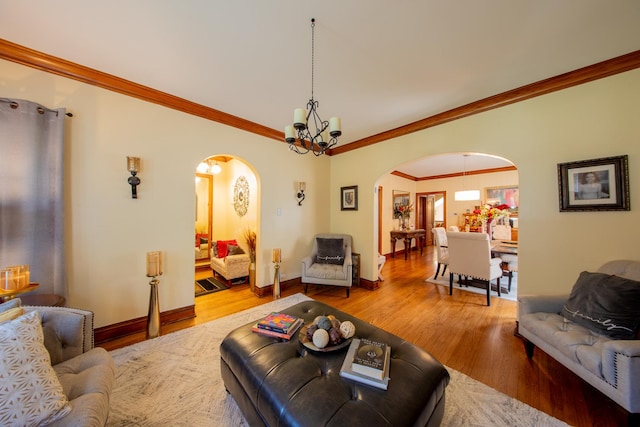 living area with arched walkways, wood finished floors, a chandelier, baseboards, and ornamental molding