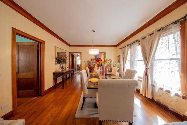 dining area featuring wood finished floors, crown molding, and baseboards