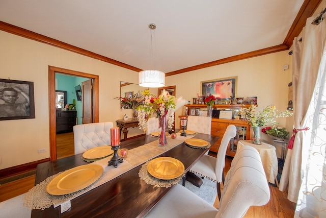 dining room with wood finished floors, crown molding, and baseboards