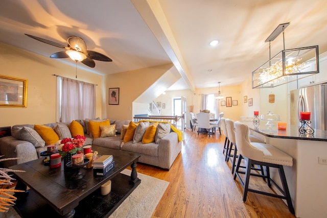 living area with a chandelier, a ceiling fan, and light wood-type flooring
