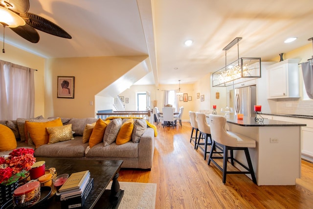 living room featuring light wood-style flooring, a ceiling fan, a chandelier, and recessed lighting