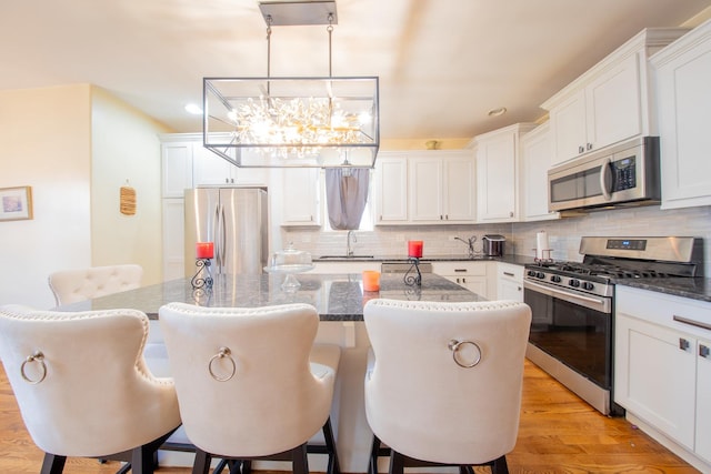kitchen with appliances with stainless steel finishes, a sink, a kitchen island, a chandelier, and backsplash