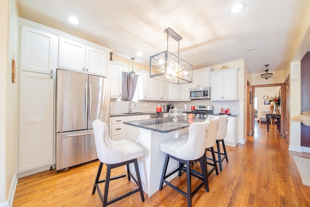 kitchen with appliances with stainless steel finishes, a sink, backsplash, white cabinets, and recessed lighting