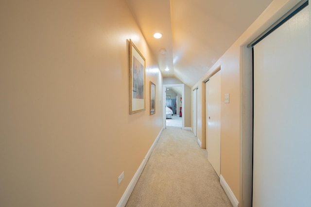 hallway with light colored carpet, recessed lighting, lofted ceiling, and baseboards
