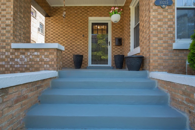 view of exterior entry featuring covered porch and brick siding