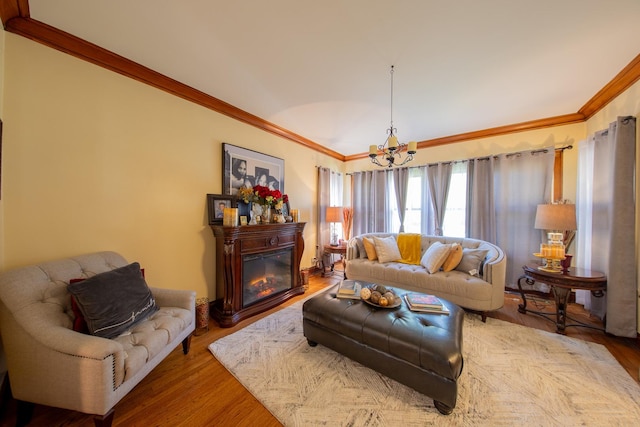 living room with crown molding, a chandelier, wood finished floors, and a glass covered fireplace