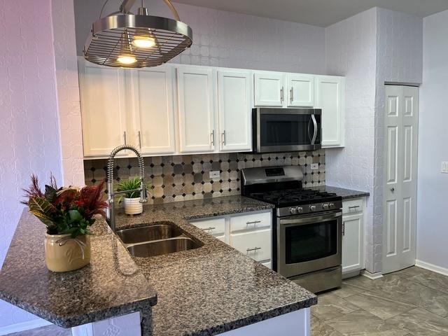 21148 W Cypress Ln, Plainfield, IL 60544 - kitchen with stainless steel appliances, a sink, and white cabinetry