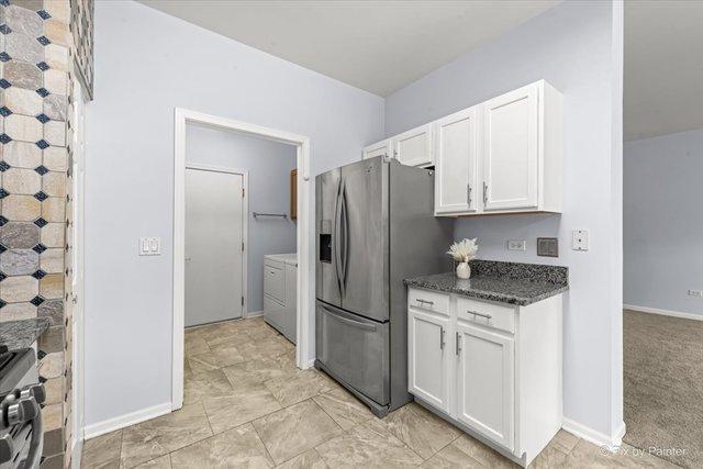 21148 W Cypress Ln, Plainfield, IL 60544 - kitchen with appliances with stainless steel finishes, white cabinets, washing machine and clothes dryer, and baseboards