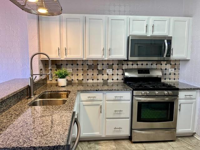 21148 W Cypress Ln, Plainfield, IL 60544 - kitchen with stainless steel appliances, a sink, white cabinets, and dark stone countertops
