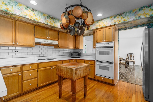 1N341 Indian Knoll Rd, West Chicago, IL 60185 - kitchen with under cabinet range hood, appliances with stainless steel finishes, brown cabinets, wallpapered walls, and light wood-style flooring