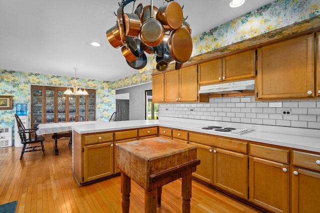 1N341 Indian Knoll Rd, West Chicago, IL 60185 - kitchen with wallpapered walls, under cabinet range hood, white electric cooktop, a peninsula, and light countertops