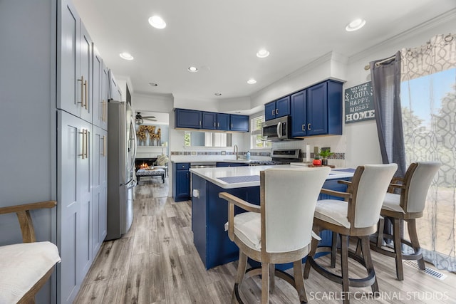 2442 La Costa Ct, Aurora, IL 60503 - kitchen featuring blue cabinets, crown molding, appliances with stainless steel finishes, light countertops, and a breakfast bar