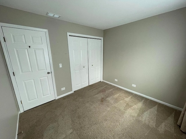 unfurnished bedroom featuring carpet, baseboards, and a closet