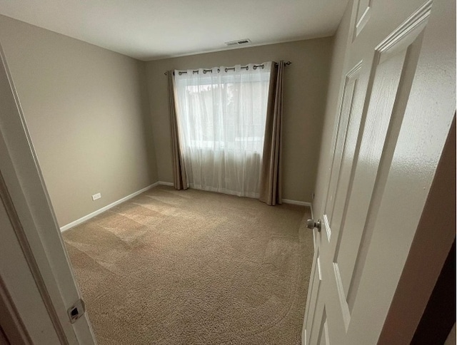 empty room featuring light colored carpet and baseboards