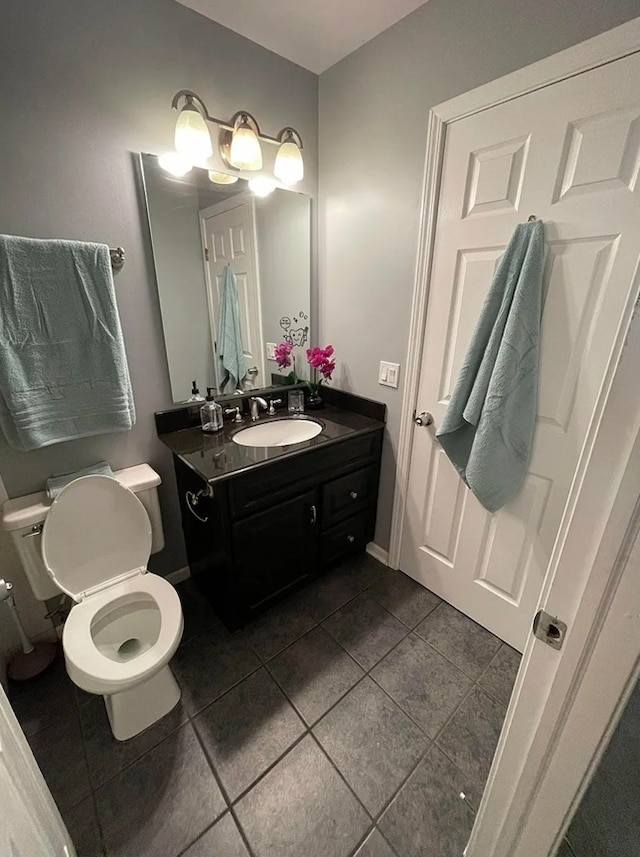 half bath featuring tile patterned floors, toilet, and vanity