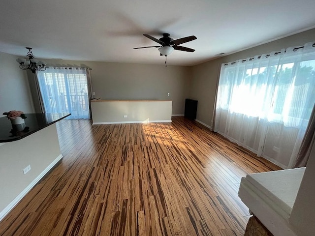 unfurnished living room featuring healthy amount of natural light, baseboards, and wood finished floors