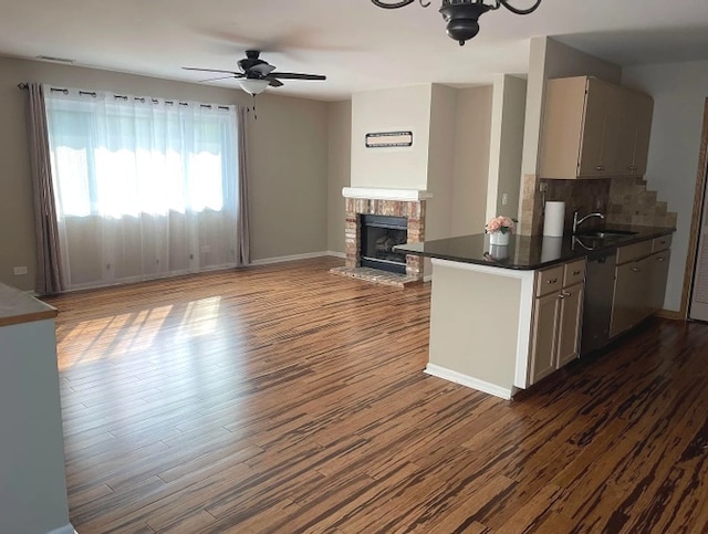kitchen with stainless steel dishwasher, dark wood finished floors, dark countertops, and a brick fireplace