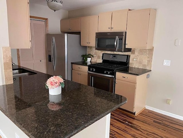 kitchen with stainless steel appliances, a sink, dark wood-type flooring, tasteful backsplash, and baseboards