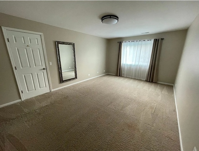 unfurnished room featuring carpet floors and baseboards