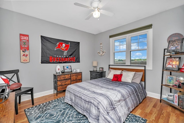 bedroom featuring wood finished floors, baseboards, and a ceiling fan
