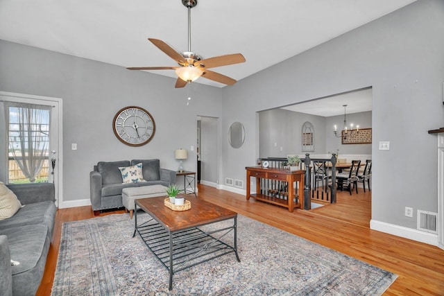 living room featuring wood finished floors, ceiling fan, a chandelier, and baseboards
