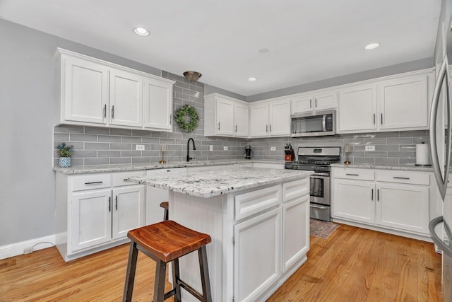 kitchen featuring appliances with stainless steel finishes, white cabinets, tasteful backsplash, a kitchen island, and recessed lighting