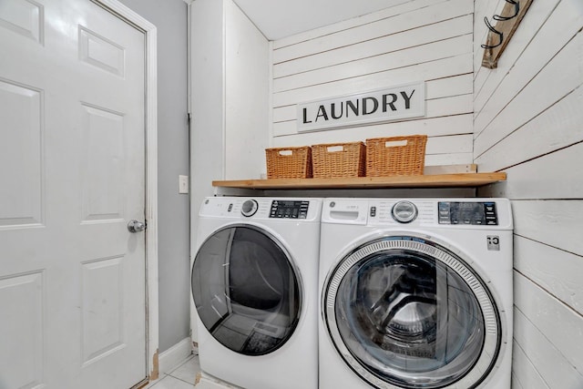 laundry room featuring washing machine and clothes dryer and wood walls
