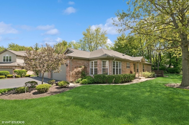 view of side of home featuring brick siding, driveway, a yard, and an attached garage