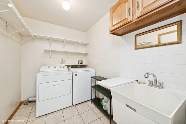 washroom featuring cabinet space, independent washer and dryer, light tile patterned flooring, and baseboards