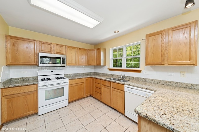 kitchen with white appliances, a sink, light tile patterned floors, backsplash, and light stone counters