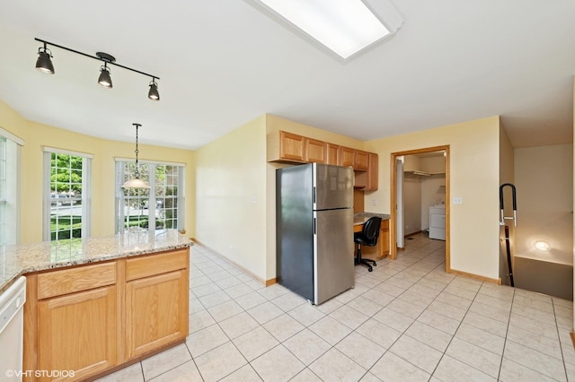 kitchen with freestanding refrigerator, washer / clothes dryer, a desk, light tile patterned flooring, and dishwasher