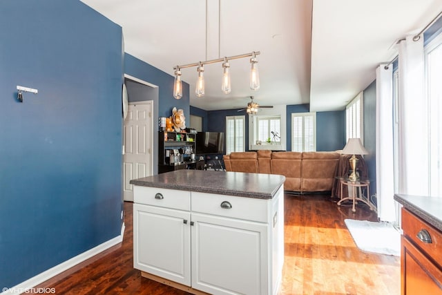 554 Truman Dr, Oswego, IL 60543 - kitchen with dark countertops, dark wood-style floors, ceiling fan, white cabinetry, and a kitchen island