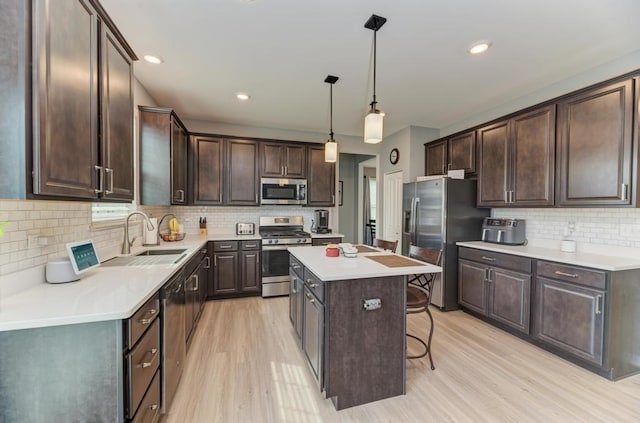kitchen with appliances with stainless steel finishes, a sink, decorative backsplash, light wood-type flooring, and dark brown cabinets