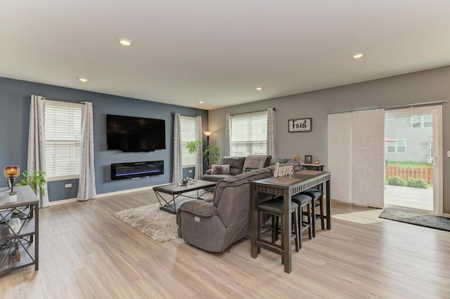living area with light wood finished floors, recessed lighting, and a glass covered fireplace