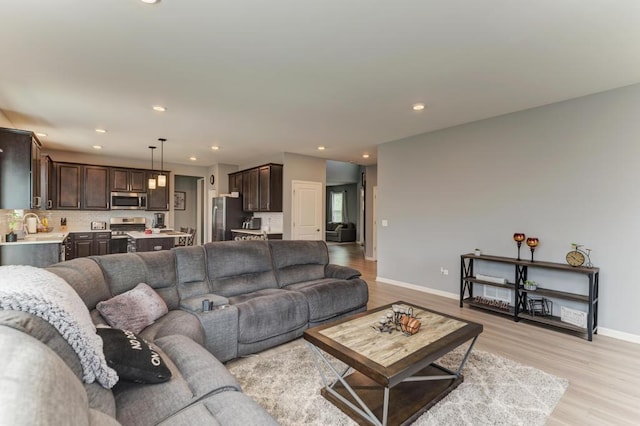 living area featuring recessed lighting, light wood-style floors, and baseboards