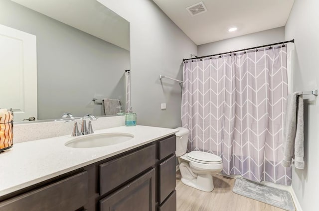 bathroom featuring wood finished floors, vanity, toilet, and curtained shower