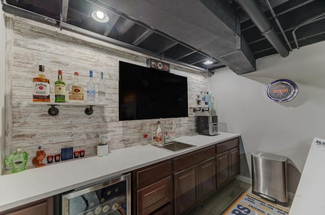 bar featuring a sink, beverage cooler, light wood-type flooring, and wood walls