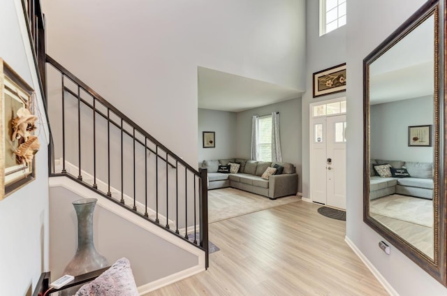 foyer with wood finished floors, a high ceiling, stairway, and baseboards