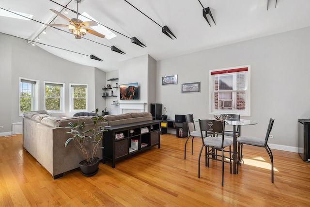 living room with rail lighting, wood finished floors, ceiling fan, baseboards, and high vaulted ceiling