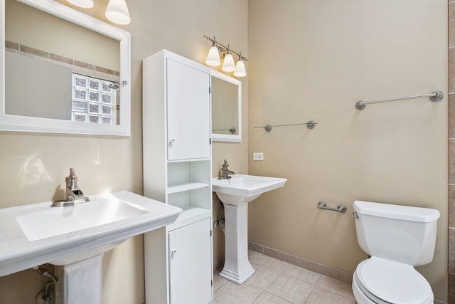 bathroom with toilet, tile patterned flooring, baseboards, and a sink