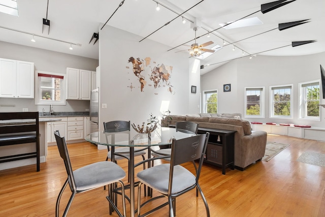 dining space with rail lighting, light wood-style flooring, ceiling fan, and high vaulted ceiling