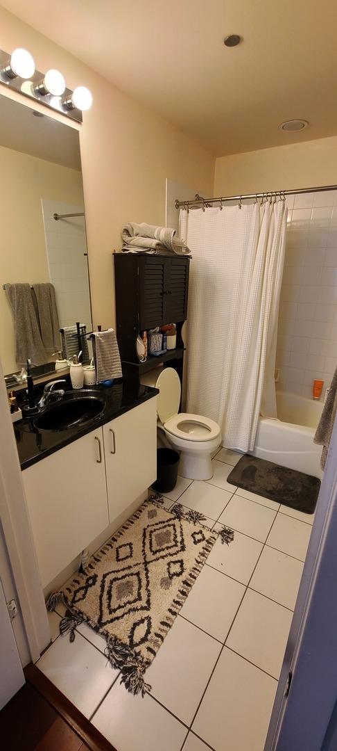 bathroom featuring toilet, tile patterned flooring, shower / bathtub combination with curtain, and vanity