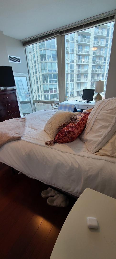 bedroom featuring a wall of windows and wood finished floors