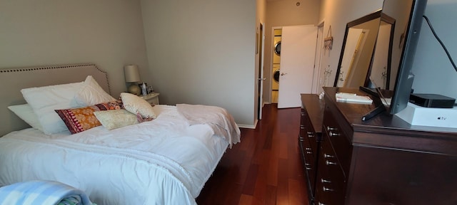 bedroom featuring stacked washer / drying machine and dark wood-style floors