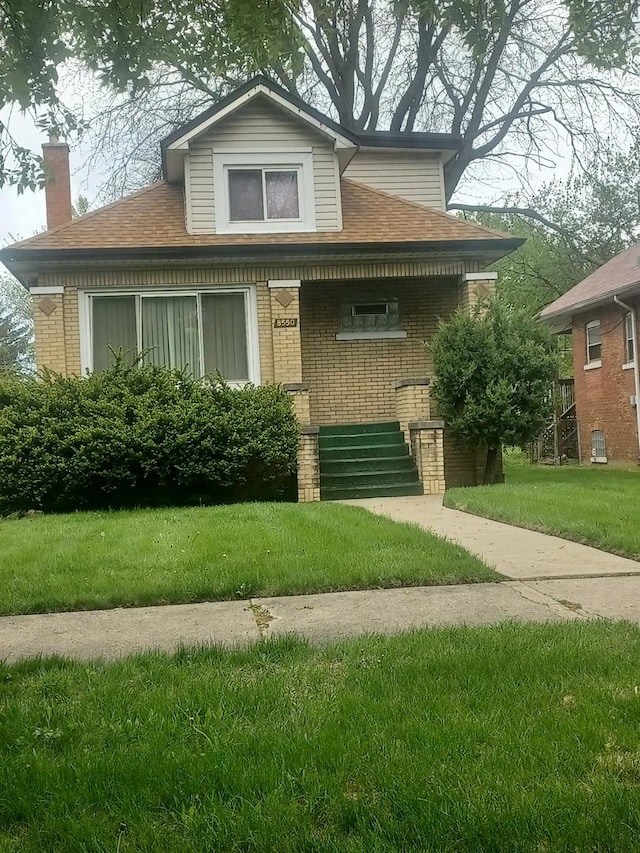 bungalow-style home featuring brick siding, a front lawn, and a chimney