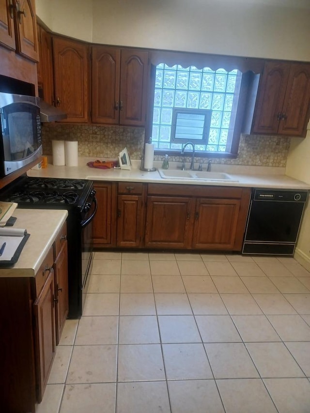 kitchen with black appliances, a sink, backsplash, light countertops, and light tile patterned floors