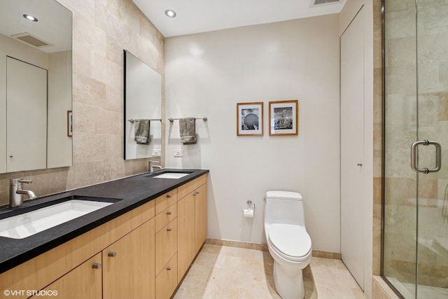 bathroom with toilet, a shower stall, double vanity, baseboards, and tile patterned floors