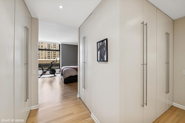 hallway featuring light wood-style flooring, recessed lighting, and baseboards